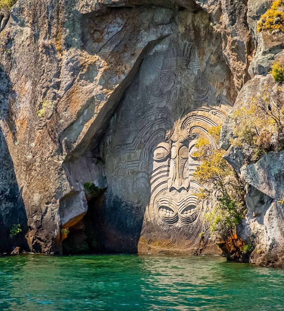 Ngātoroirangi rock carving above the turquoise water of Mine Bay, Lake Taupō